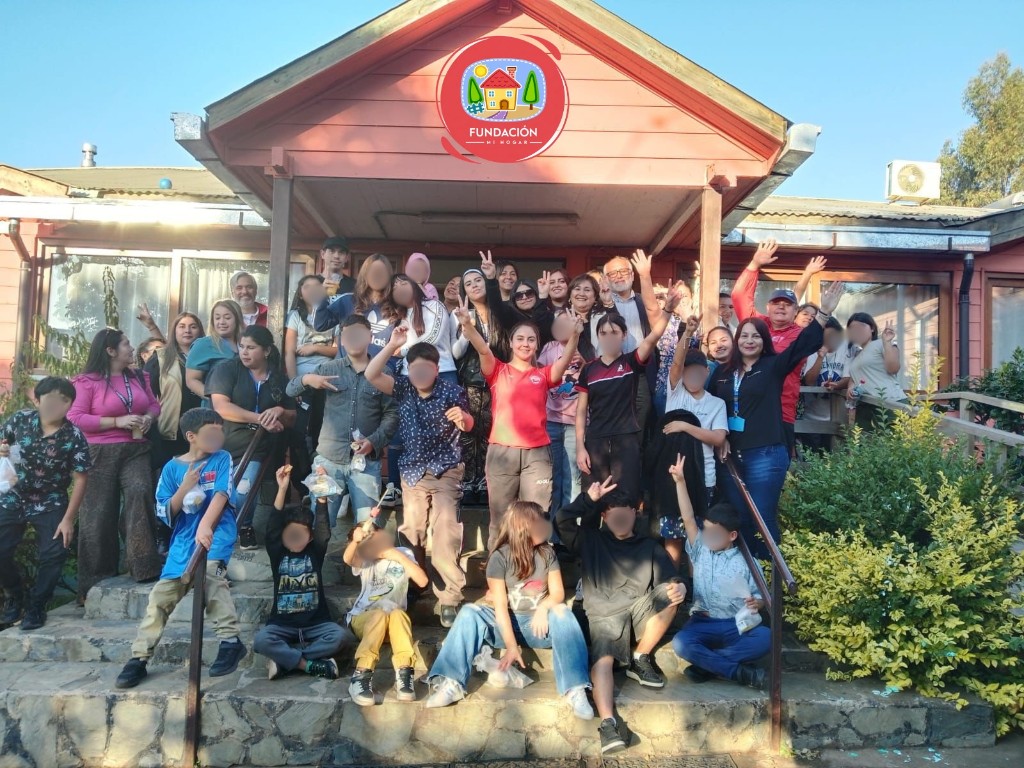 Comunidad de Fundación Mi Hogar reunida en la entrada del hogar, con rostros difuminados para resguardar la identidad de niñas, adolescentes y familias.